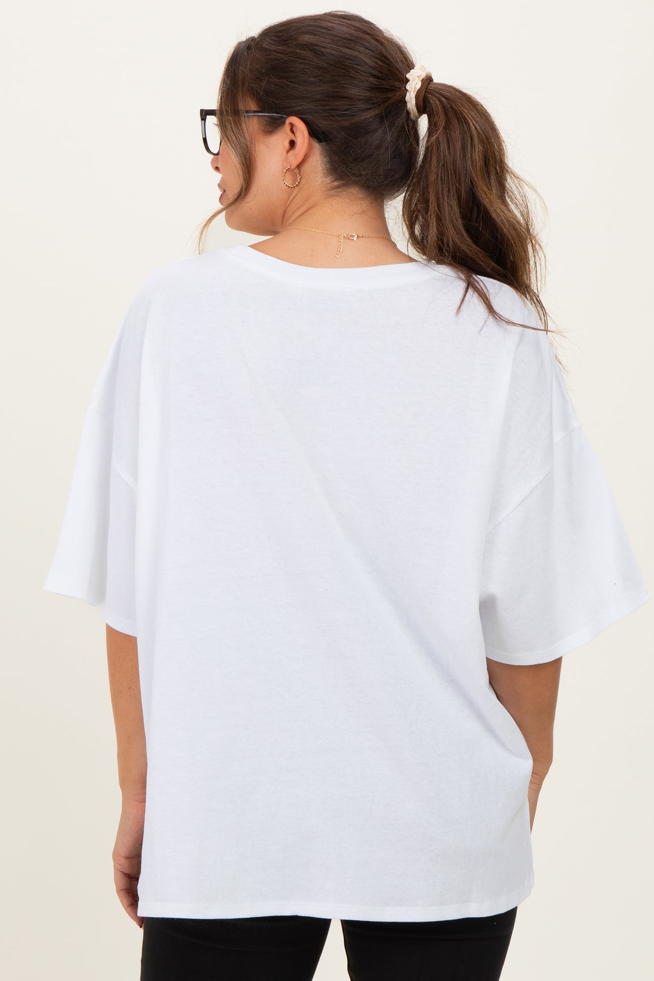 woman wearing a loose-fitting white maternity t-shirt with short sleeves and a curved hem, seen from the back