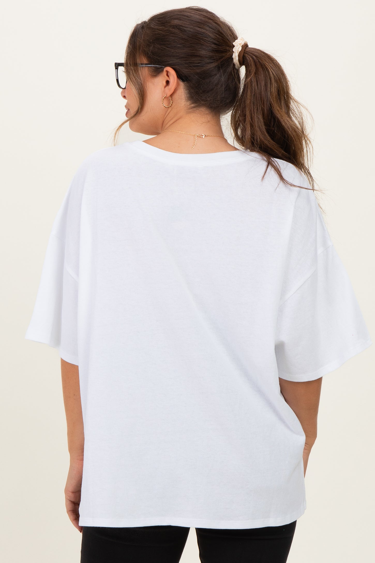 woman wearing a loose-fitting white maternity t-shirt with short sleeves and a curved hem, seen from the back