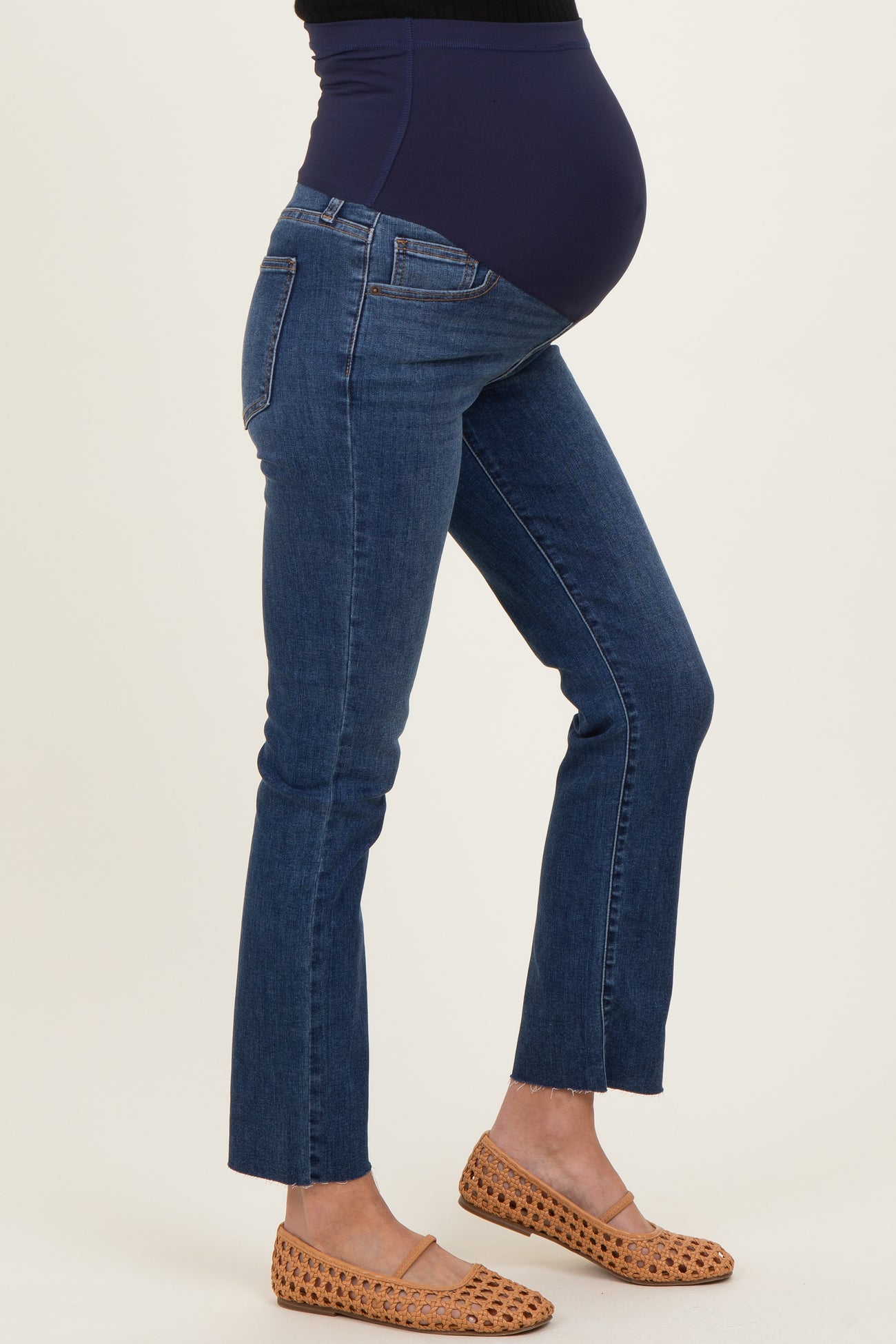 woman wearing blue maternity jeans with a supportive belly panel and cropped hem