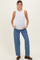 woman wearing a white sleeveless maternity top and blue wide-leg jeans, showing a visible baby bump