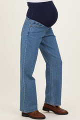 woman wearing light blue maternity jeans with a navy blue over-the-bump panel and a visible baby bump