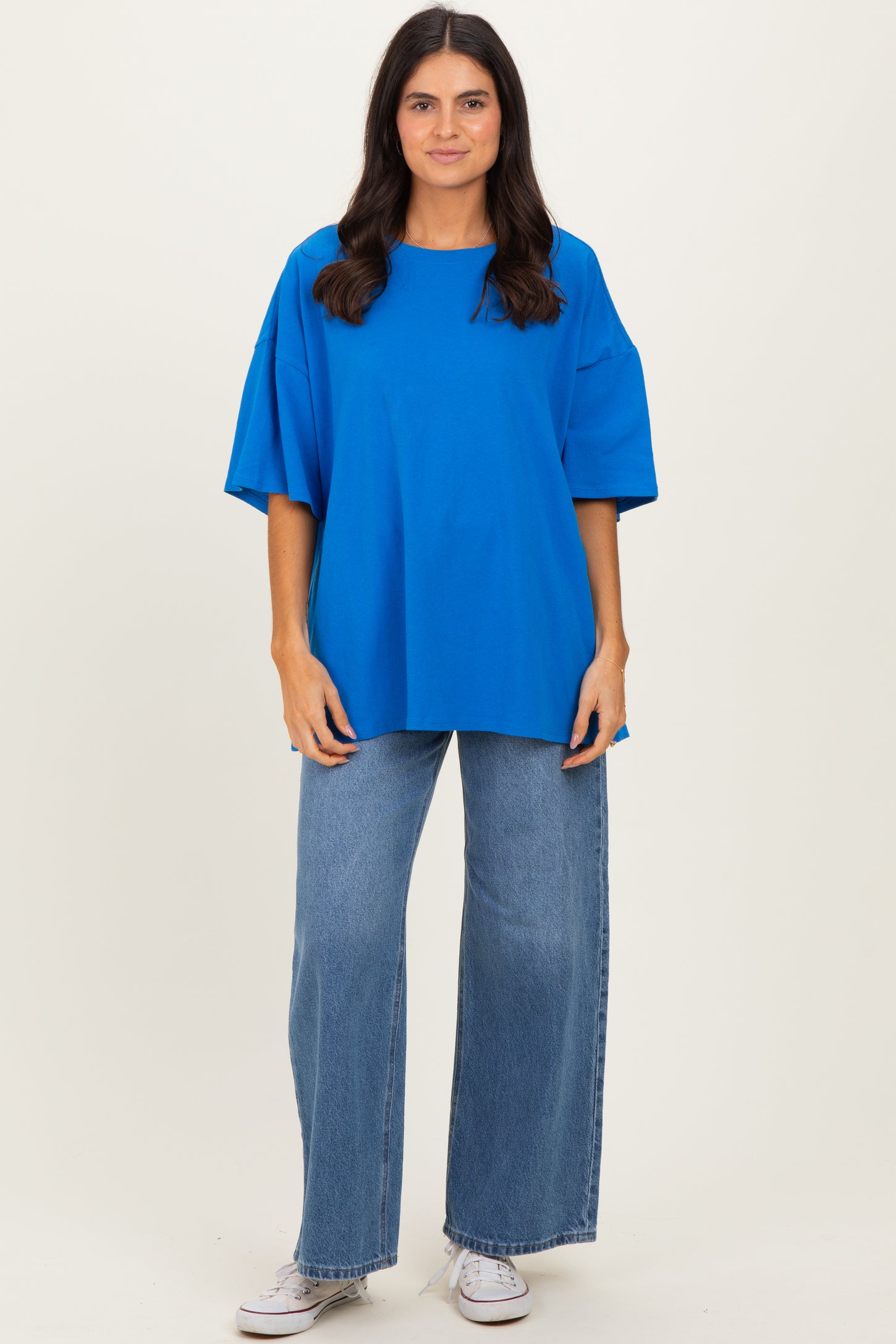 woman wearing a vibrant blue oversized t-shirt and loose-fitting jeans with white sneakers