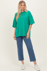 woman wearing an oversized green t-shirt with short sleeves and high-waisted denim jeans, styled with white sneakers