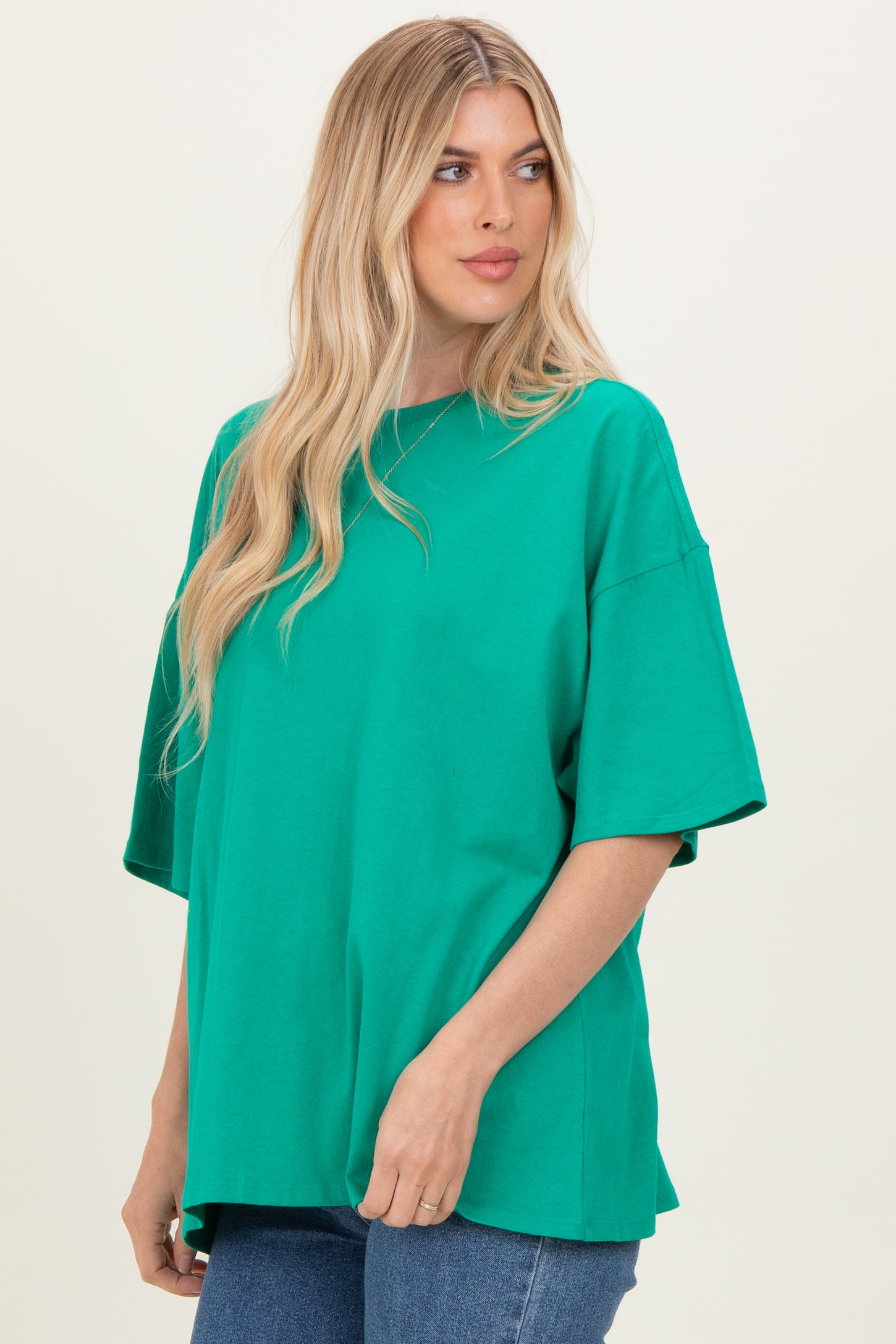 woman wearing a bright green oversized t-shirt with short sleeves and relaxed fit, styled with blue jeans