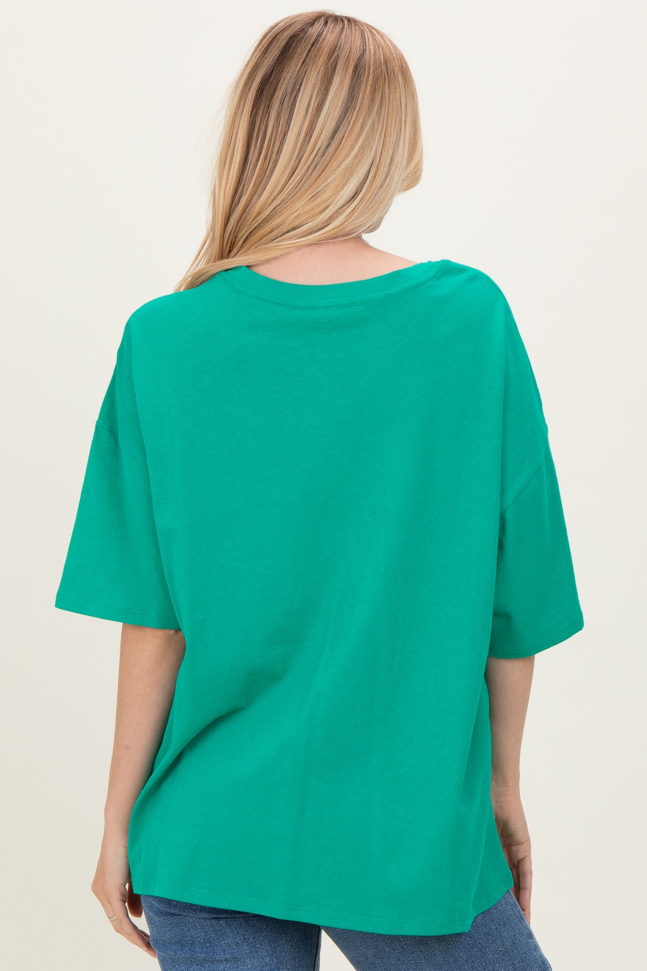 woman wearing a green oversized t-shirt, styled with a relaxed fit, seen from the back
