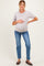 woman wearing a light purple maternity t-shirt and blue jeans, holding her baby bump