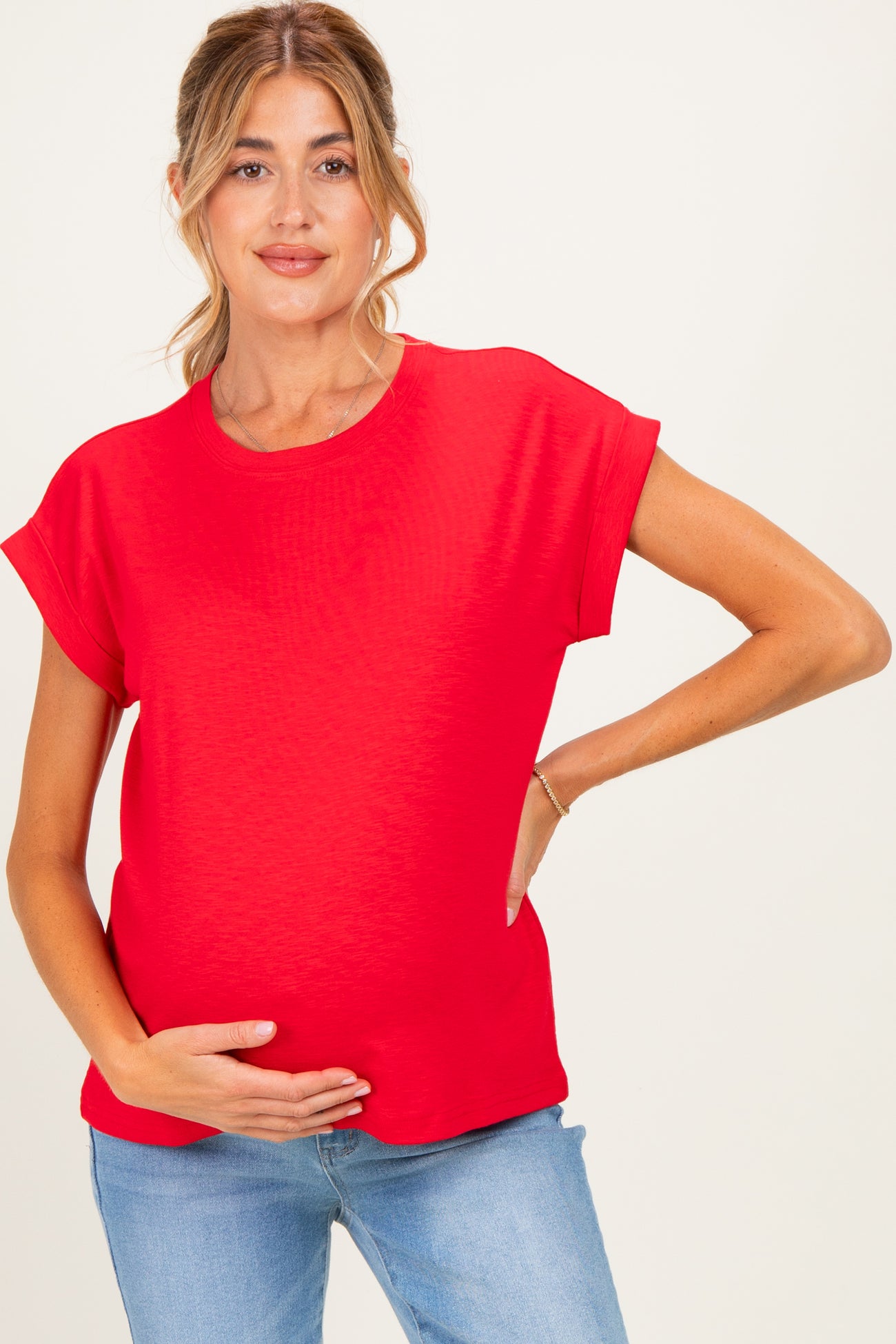 woman wearing a red short sleeve maternity top and holding her baby bump