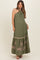 woman wearing an olive green halter neck maternity dress with embroidered palm leaf details and a flowy skirt