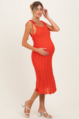 woman wearing a bright orange knit maternity dress with tie straps and a visible baby bump