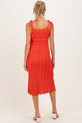 woman wearing a vibrant orange maternity dress with tie shoulder straps and a midi length