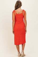 woman wearing a coral knee-length knit dress with tie straps, showcased from the back