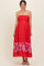 woman wearing a red maternity maxi dress with floral print at the hem and spaghetti straps, showing her baby bump