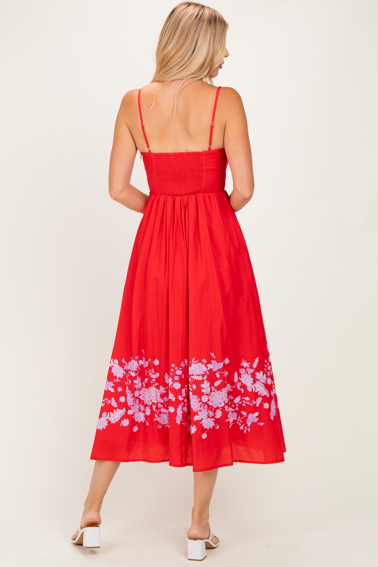 woman wearing a red floral print midi dress with spaghetti straps and a smocked bodice, shown from the back