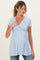 woman wearing a light blue short sleeve maternity top, featuring a wrap design and a visible baby bump