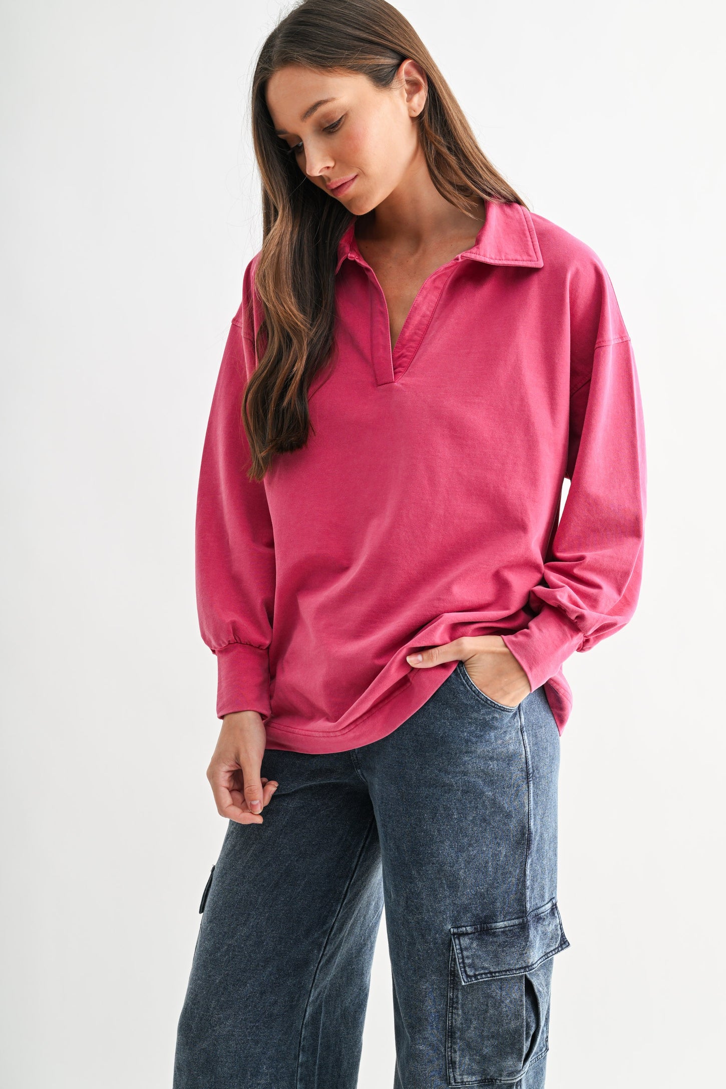 woman wearing a pink long sleeve polo-style shirt with a loose fit and high collar paired with dark cargo pants
