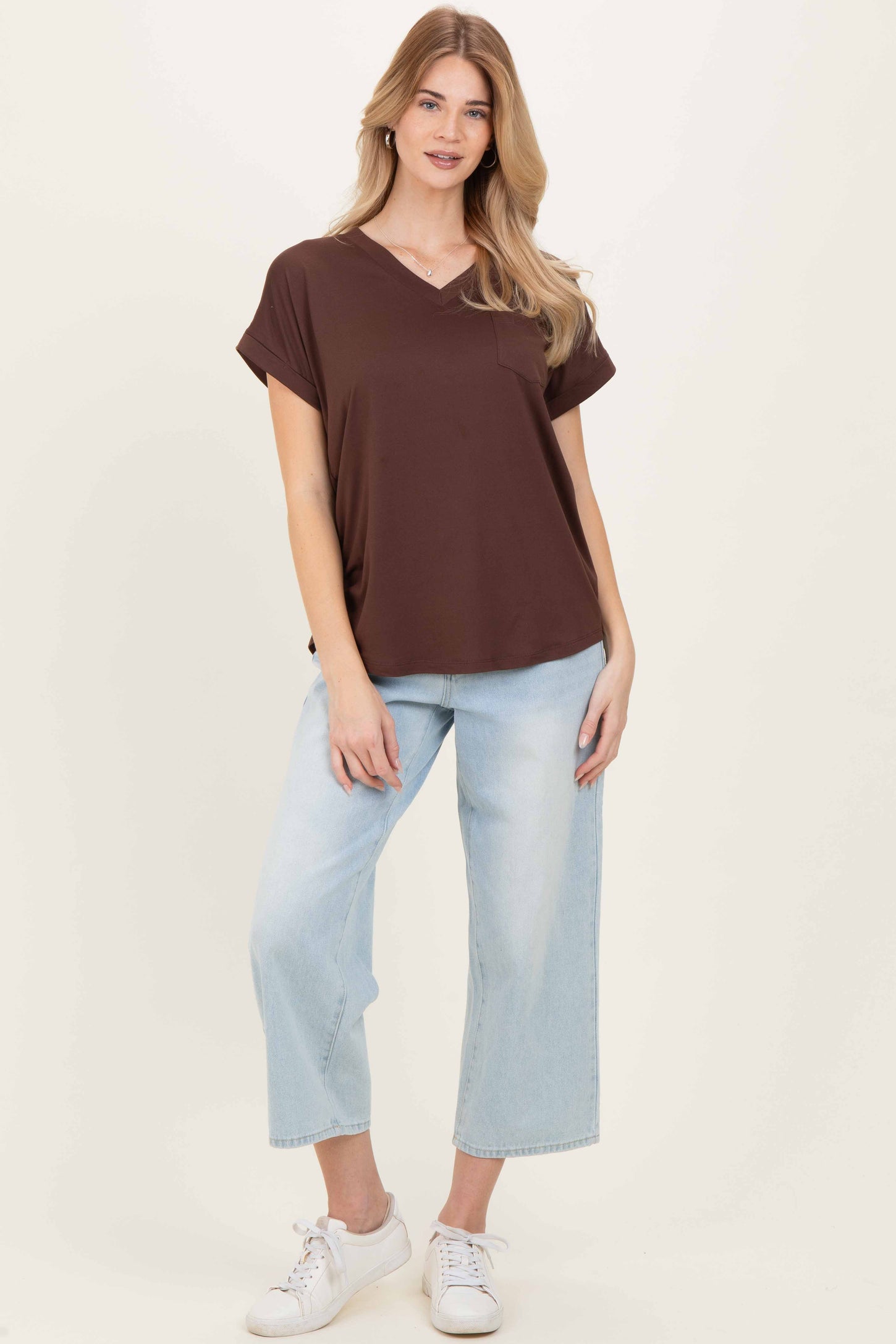 woman wearing a brown short sleeve v-neck top with a pocket and light blue cropped wide-leg jeans