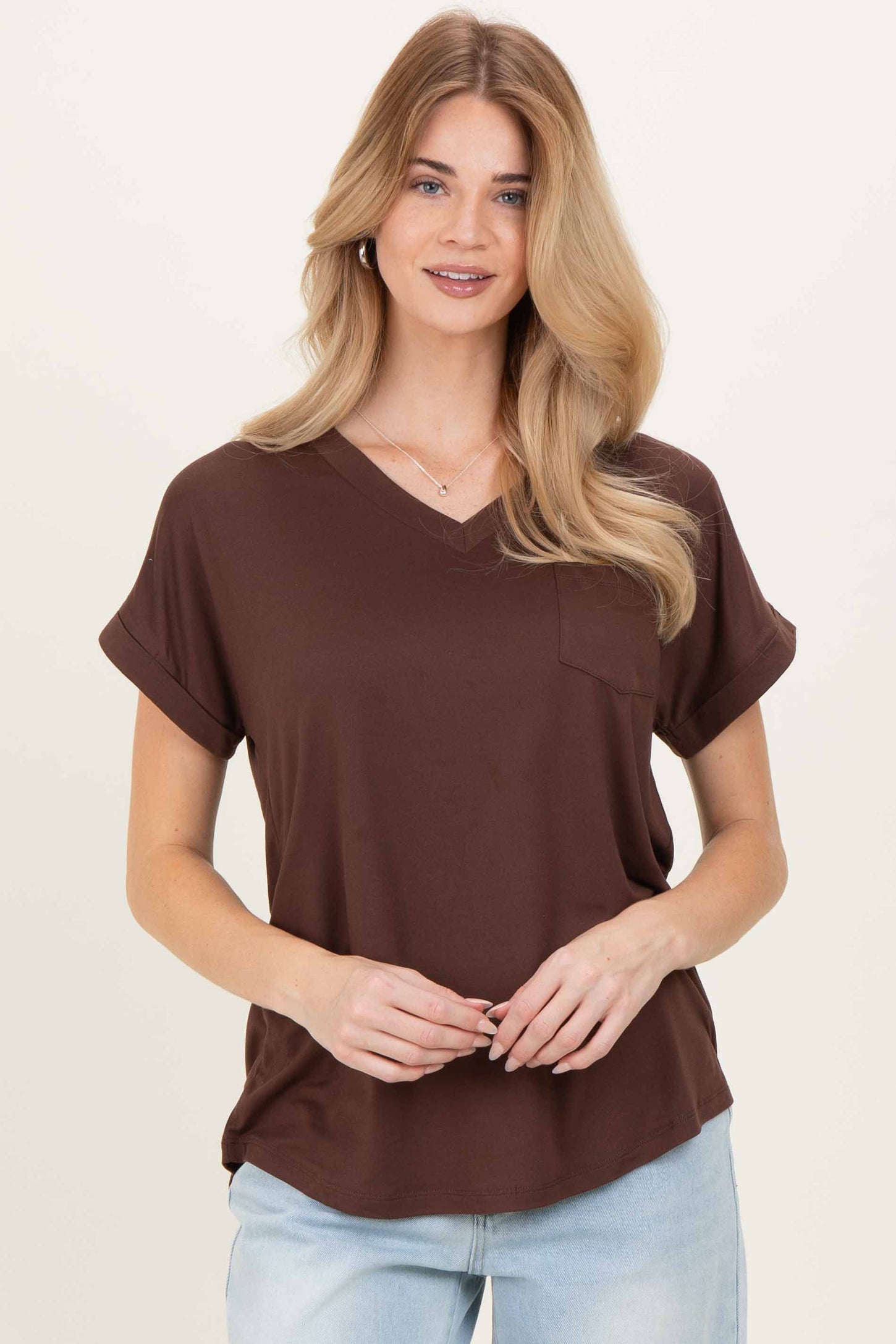woman wearing a brown v-neck t-shirt with rolled short sleeves and a front pocket