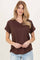 woman wearing a brown v-neck t-shirt with rolled short sleeves and a front pocket