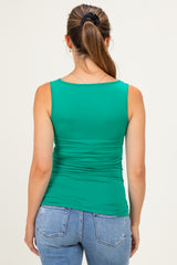 woman wearing a green maternity tank top with ruching details, showing a smooth back and styled with jeans