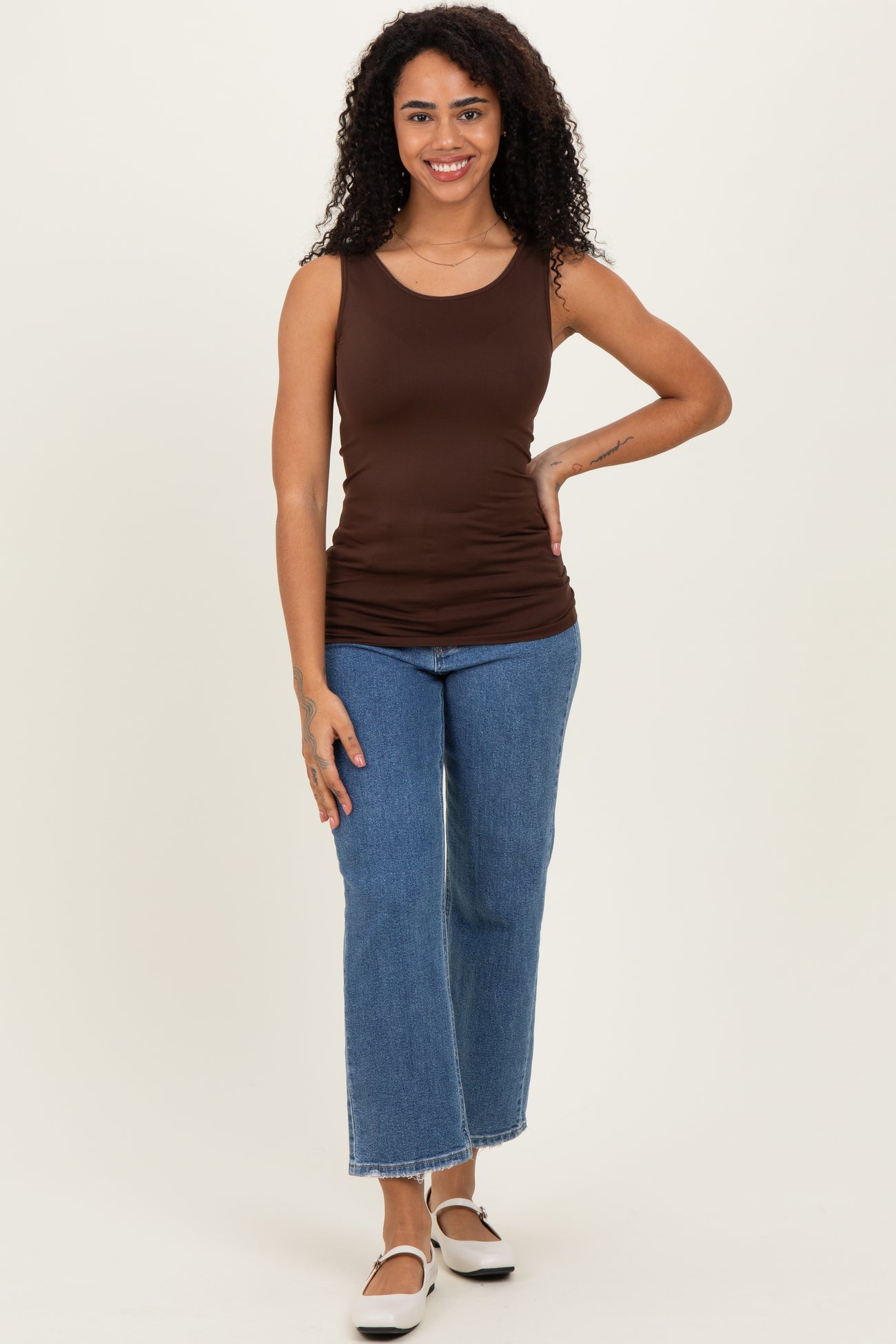 woman wearing a dark brown sleeveless top and high-waisted blue flared jeans