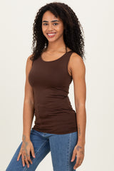 woman wearing a brown fitted tank top and blue jeans, smiling with curly hair