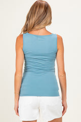 woman wearing a light blue maternity tank top with gathered sides and white shorts, viewed from the back