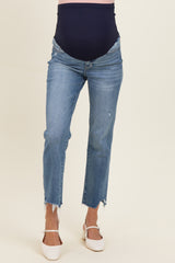 woman wearing a pair of light wash maternity jeans with a frayed hem and a navy blue over-the-bump band, showing baby bump