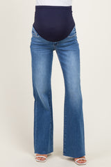 woman wearing a pair of blue maternity flared jeans with a dark navy belly band