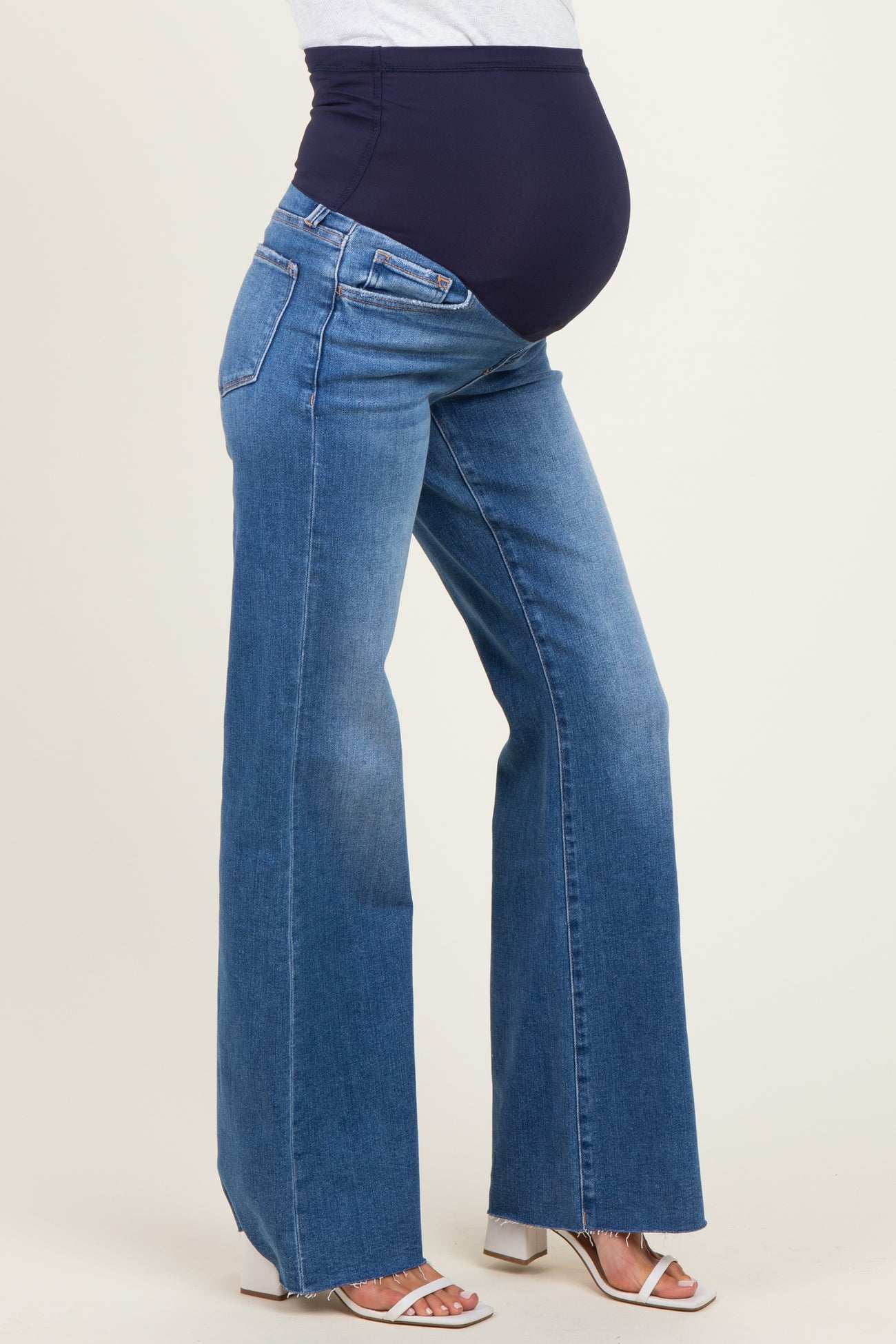woman wearing blue wide-leg maternity jeans with a navy over-the-bump waistband and a visible baby bump