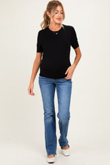 woman wearing a black short sleeve maternity top and blue flared maternity jeans, showing her baby bump