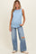 woman wearing a light blue ribbed maternity tank top and distressed wide-leg jeans with a visible baby bump