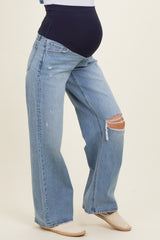 woman wearing light blue distressed wide-leg maternity jeans with a dark blue over-the-bump waistband and visible baby bump