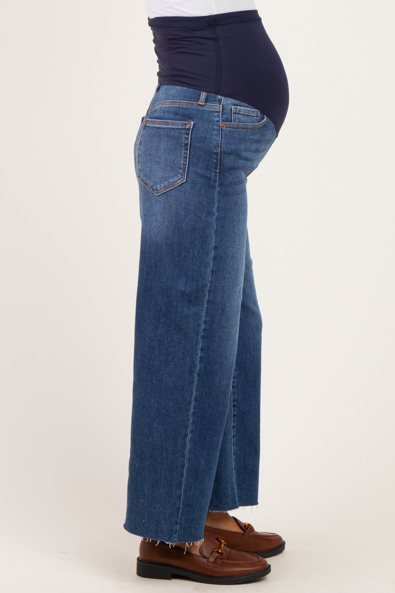 woman wearing blue wide-leg maternity jeans with a belly panel, showing her baby bump