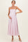 woman wearing a light pink spaghetti strap maternity dress and gently holding her baby bump