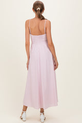 woman wearing a light pink maternity maxi dress with spaghetti straps and smocked back, standing with her back to the camera