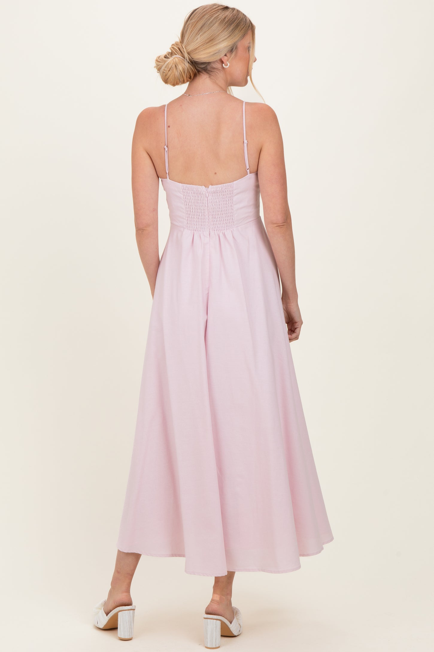 woman wearing a pink backless maxi dress with a smocked bodice and adjustable straps