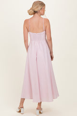 woman wearing a pink backless maxi dress with a smocked bodice and adjustable straps