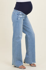woman wearing light blue maternity flared jeans with a dark blue over-the-bump waistband and a visible baby bump
