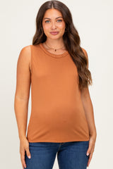 woman wearing a rust-colored sleeveless maternity top with lace detailing at the neckline and a visible baby bump