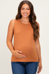 woman wearing a rust-colored sleeveless maternity top and holding her baby bump