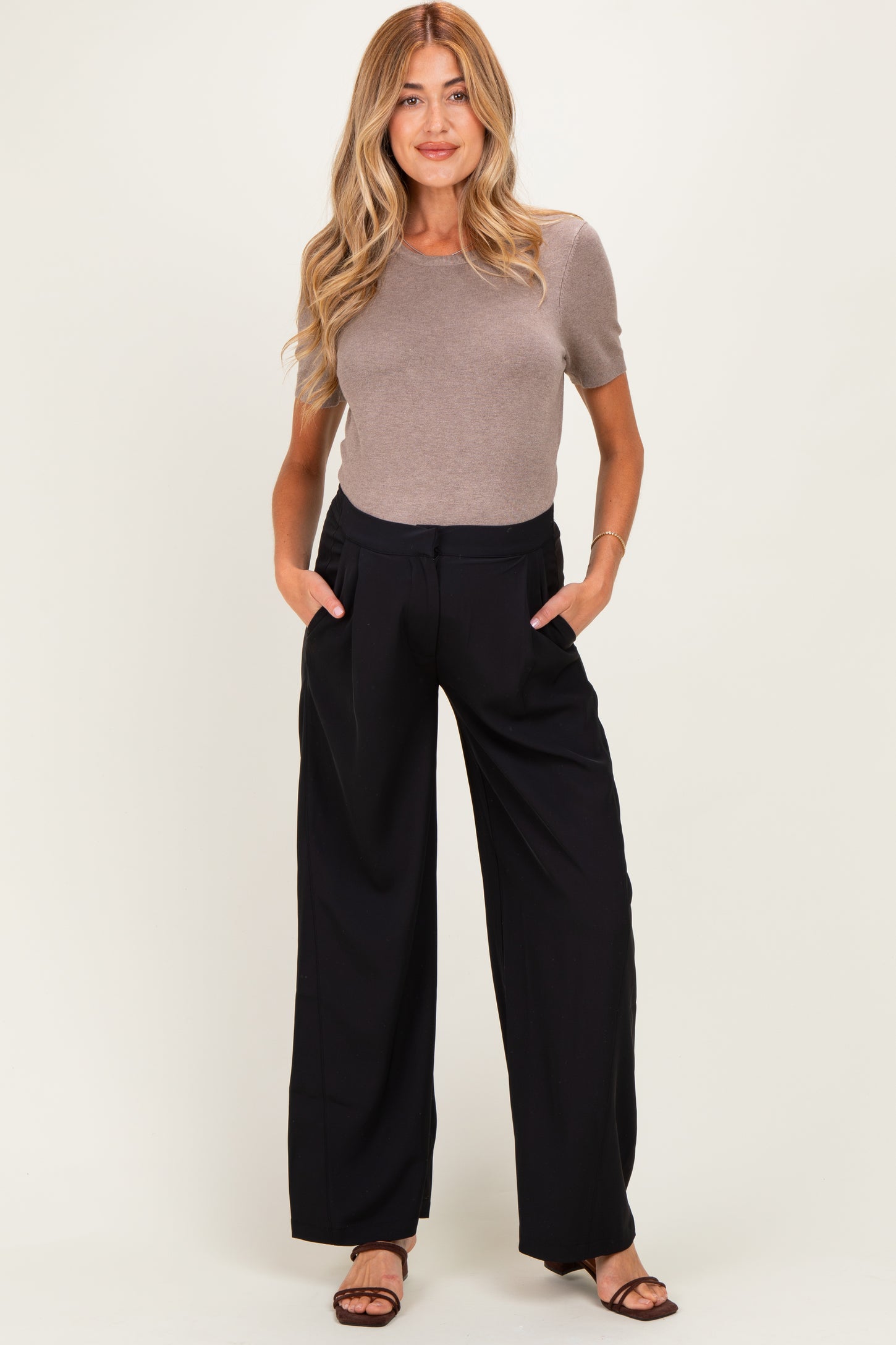woman wearing a fitted brown short sleeve top and black wide leg maternity pants with pockets