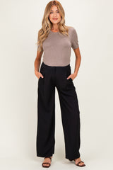 woman wearing a fitted brown short sleeve top and black wide leg maternity pants with pockets