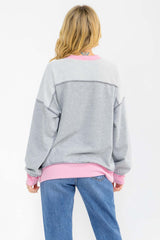 woman wearing a gray and pink oversized sweatshirt, viewed from the back, with ribbed cuffs and hem
