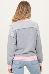 woman wearing a gray and pink maternity sweatshirt with a relaxed fit and ribbed cuffs, showing the back view