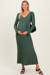 woman wearing a green long sleeve maternity dress with pleats, holding her baby bump