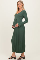 woman wearing a dark green ribbed maternity dress with a tie waist and a visible baby bump