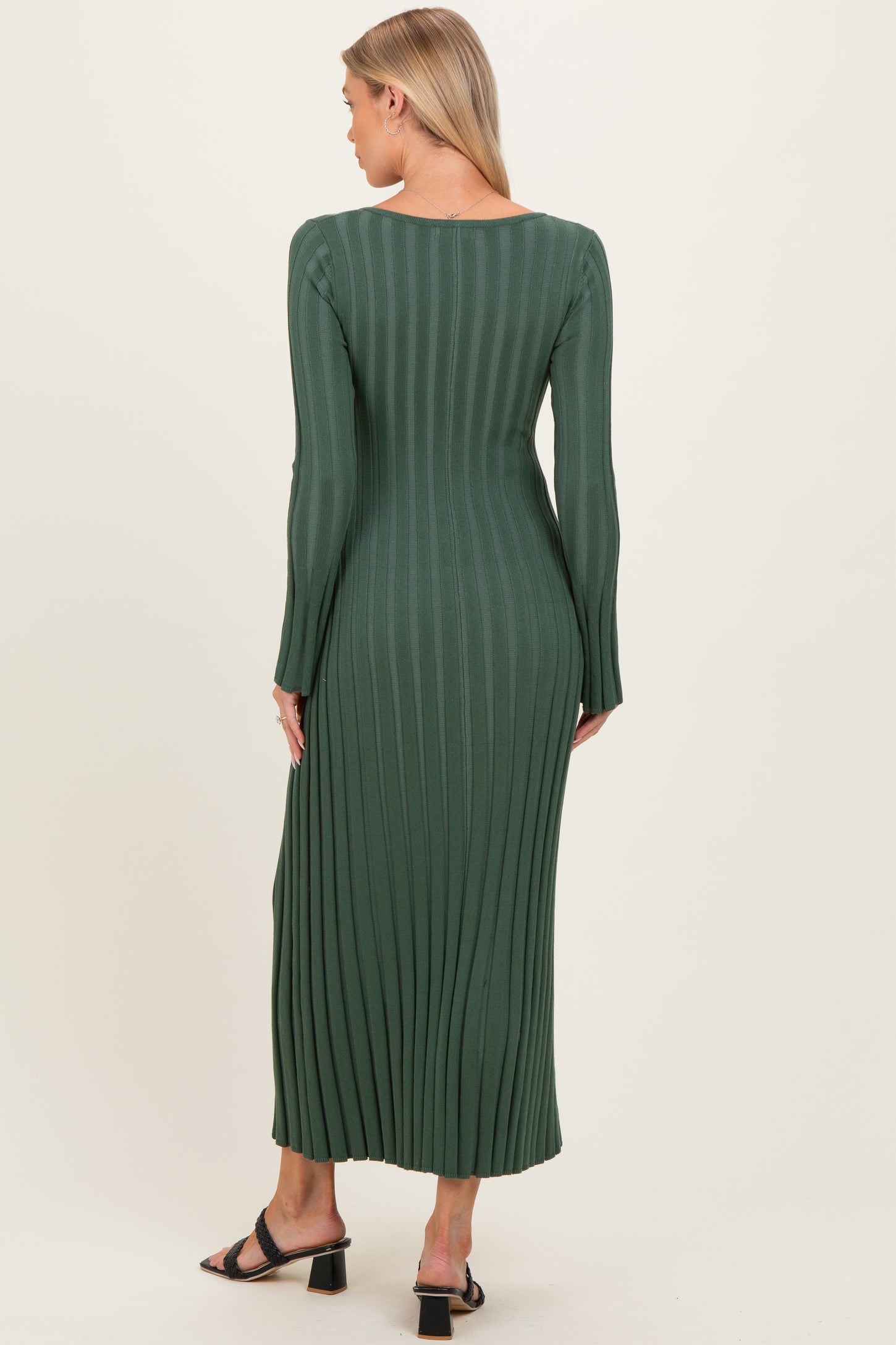 woman wearing a dark green maternity ribbed maxi dress with long sleeves and a fitted silhouette