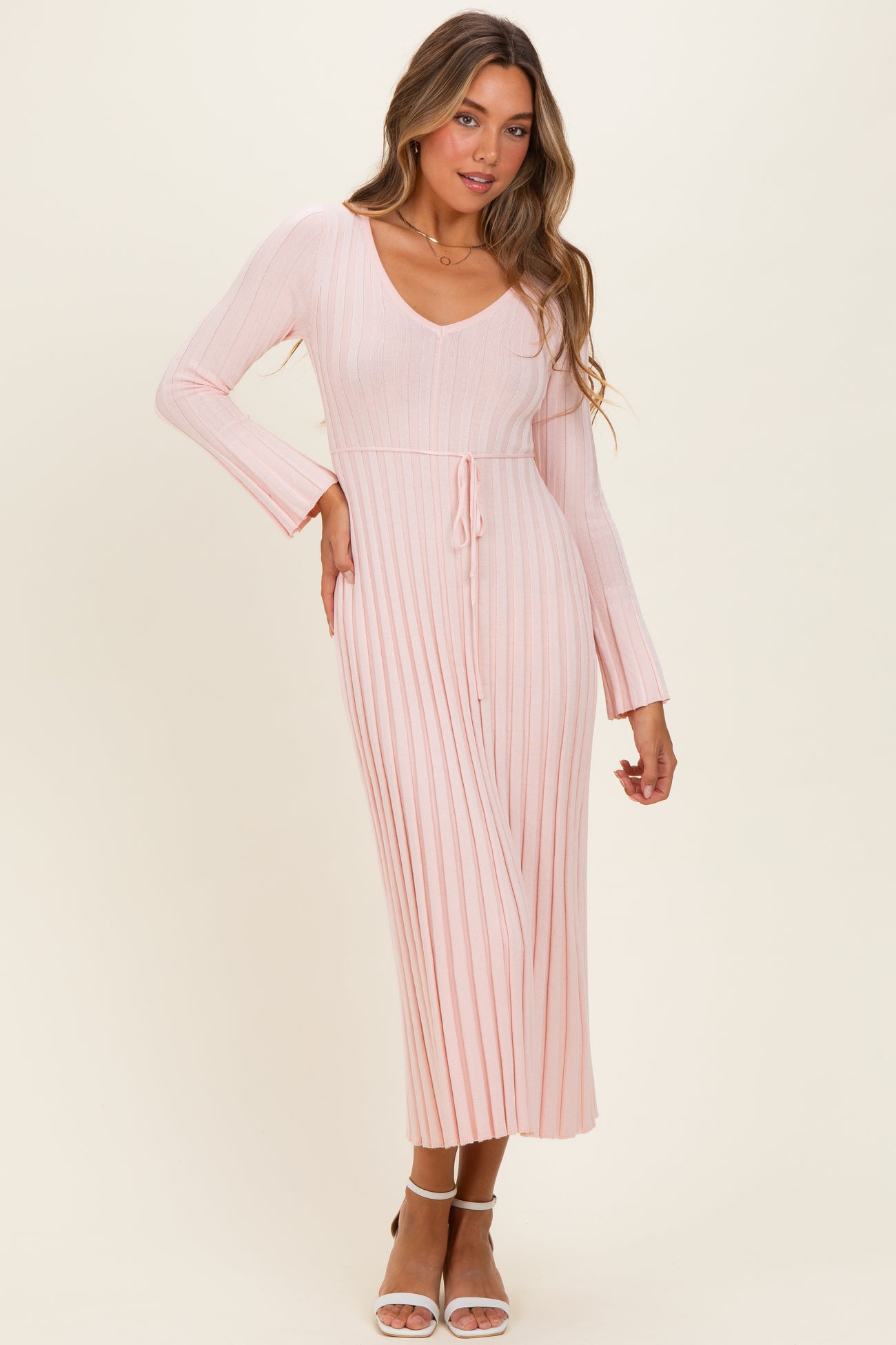 woman wearing a pink ribbed long sleeve midi dress with a v-neck and tie waist detail