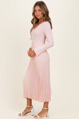 woman wearing a light pink ribbed midi dress with long sleeves and a tie waist detail