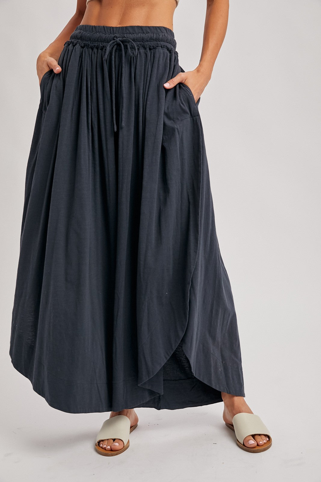 woman wearing a black maxi skirt with an elastic waistband and pockets, styled with light sandals